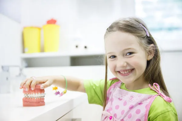 Child holding a model of teeth and smiling